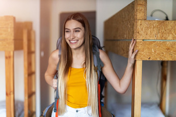 A girl walks through a hostel dorm.