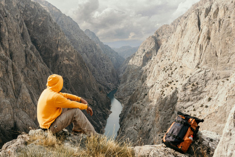 A solo travelling man sat atop a mountain.
