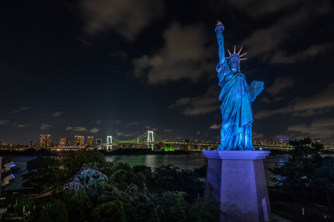 A nighttime shot of an illuminated Statue of Liberty.